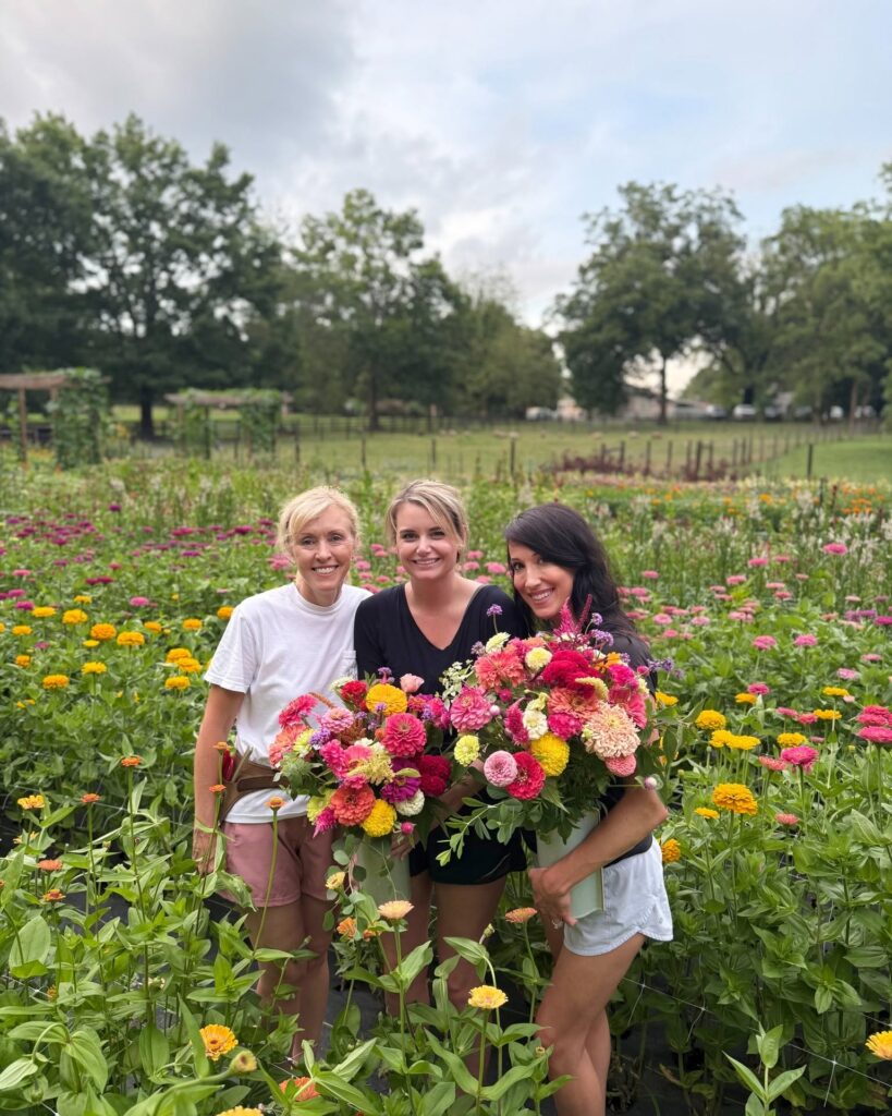 three women holding flowers in a field