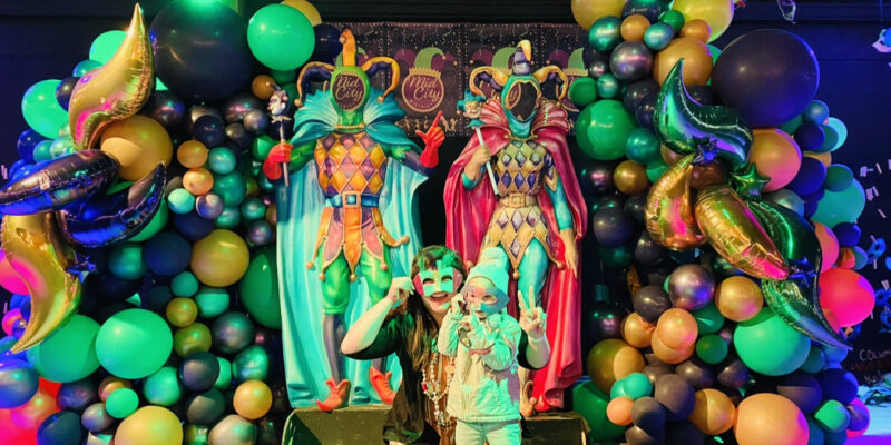 people posing in front of Mardi Gras decorations